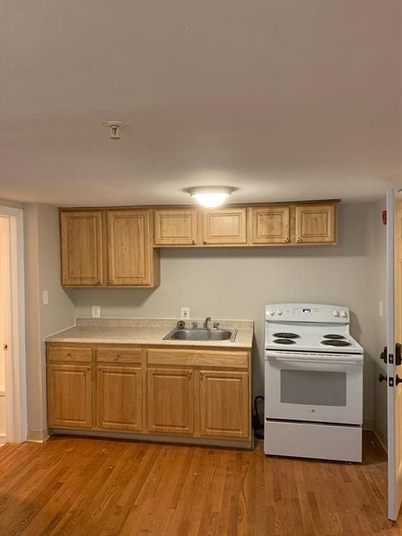 kitchen with light wood-style floors, electric range, light countertops, and a sink