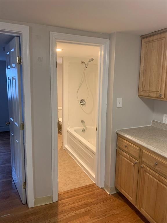 bathroom featuring tub / shower combination, wood finished floors, and toilet