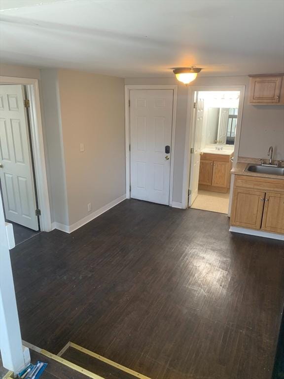 interior space with baseboards, dark wood finished floors, a sink, and light countertops