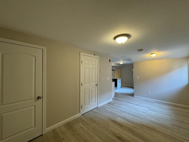 corridor with baseboards and light wood-style floors