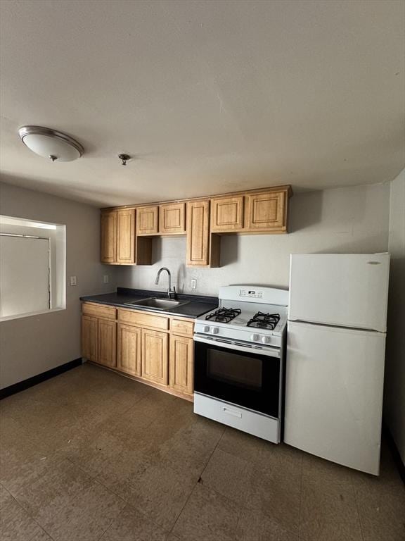 kitchen featuring dark floors, white appliances, a sink, baseboards, and dark countertops