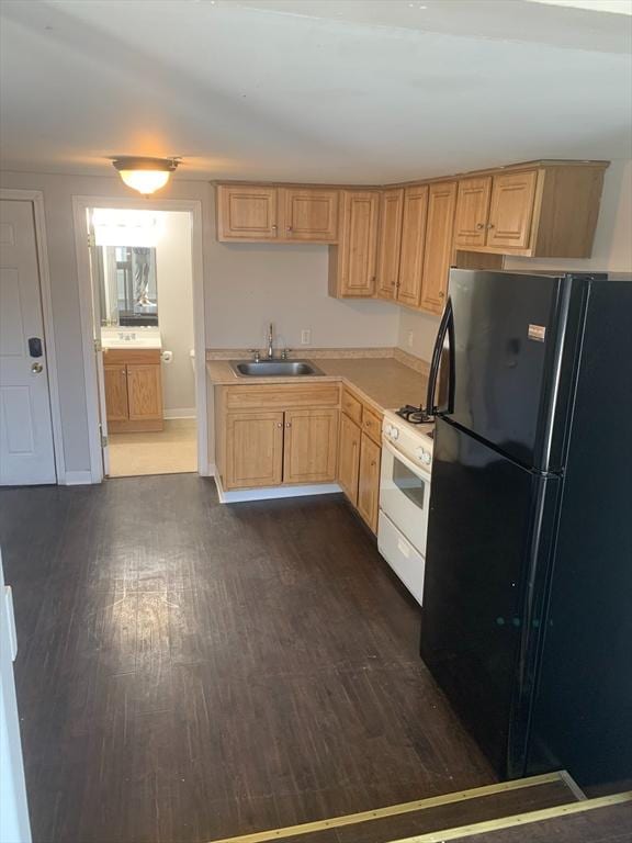 kitchen featuring white range with gas cooktop, dark wood-style flooring, a sink, and freestanding refrigerator