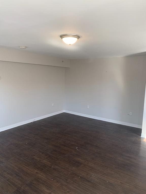 unfurnished room with dark wood-style flooring and baseboards