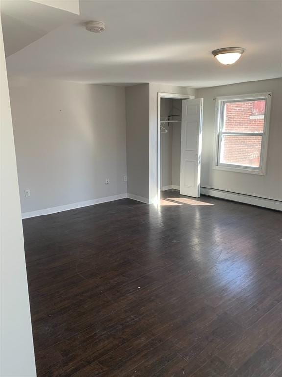 spare room with dark wood-style floors, baseboard heating, and baseboards