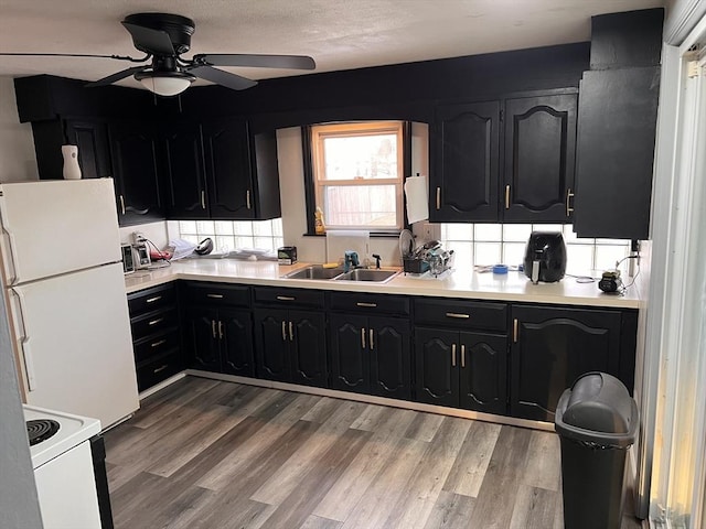 kitchen with white appliances, hardwood / wood-style flooring, ceiling fan, and sink