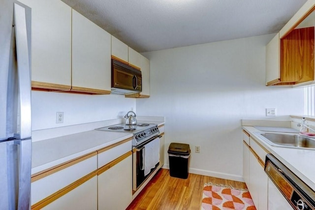 kitchen with black microwave, white dishwasher, electric range oven, freestanding refrigerator, and a sink