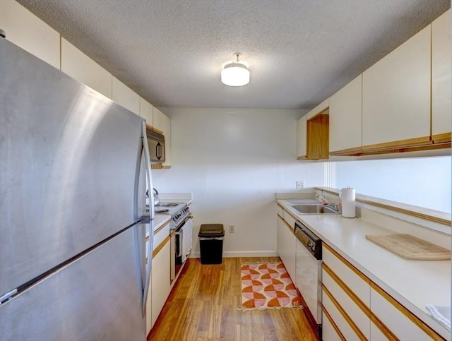 kitchen with freestanding refrigerator, a sink, electric stove, light wood-style floors, and white dishwasher