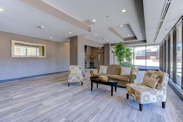 living room featuring wood finished floors, healthy amount of natural light, baseboards, recessed lighting, and a raised ceiling