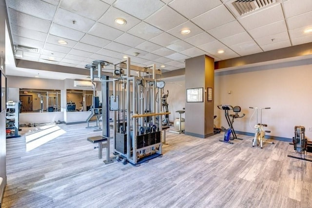 exercise room with wood finished floors, baseboards, and a drop ceiling