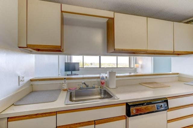 kitchen with dishwasher, a sink, light countertops, and a textured ceiling