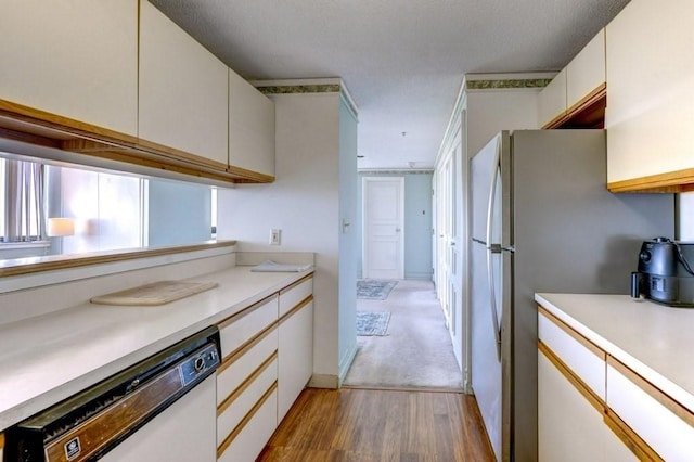kitchen featuring white dishwasher, light wood-style floors, light countertops, and white cabinets