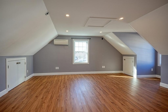 bonus room with wood-type flooring, vaulted ceiling, and a wall mounted AC