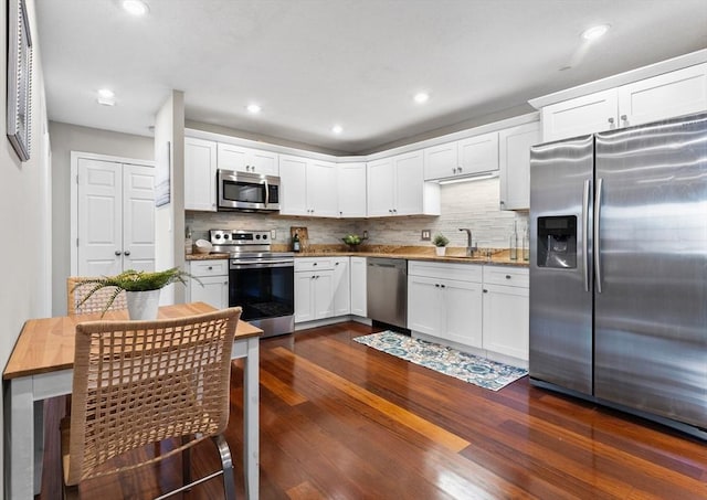 kitchen with white cabinetry, decorative backsplash, appliances with stainless steel finishes, and dark wood-type flooring