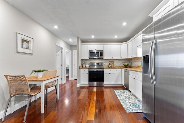 kitchen featuring decorative backsplash, white cabinets, appliances with stainless steel finishes, and dark hardwood / wood-style flooring