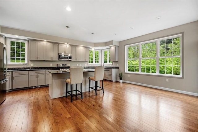 233A Green St Unit A, Boylston, MA 01505 - kitchen with appliances with stainless steel finishes, a breakfast bar area, a center island, gray cabinets, and light wood-style floors