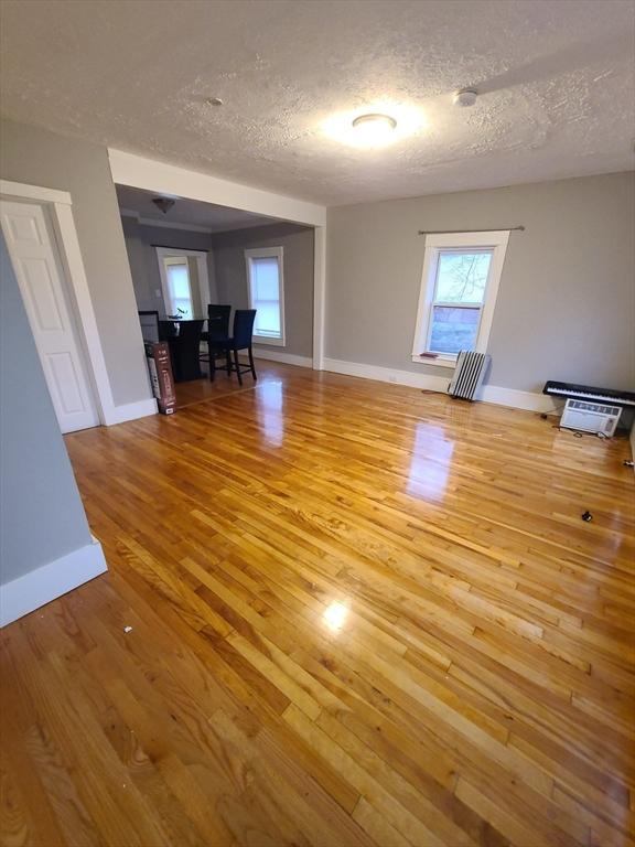 unfurnished room with wood-type flooring and a textured ceiling