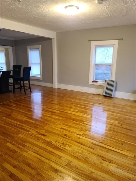 unfurnished room with hardwood / wood-style floors, a textured ceiling, and radiator