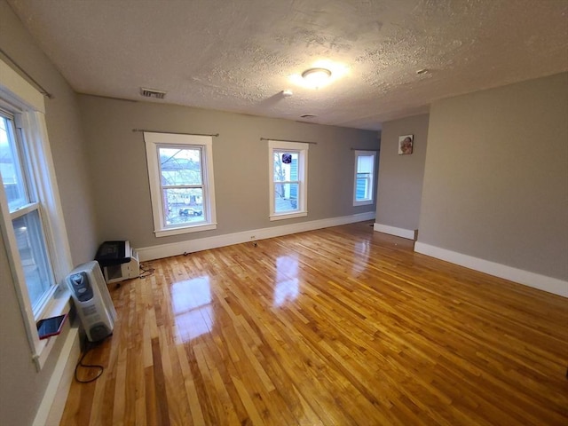 empty room featuring wood-type flooring, a textured ceiling, and heating unit