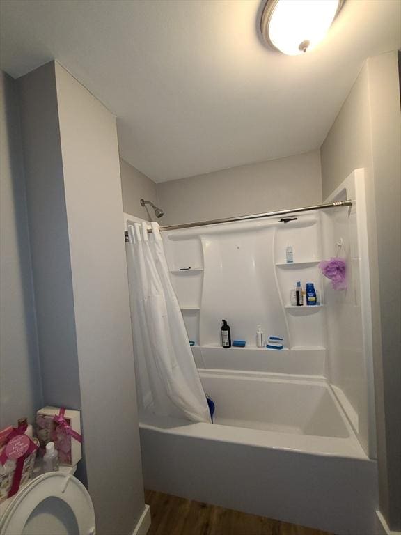 bathroom with hardwood / wood-style flooring and shower / bathtub combination with curtain