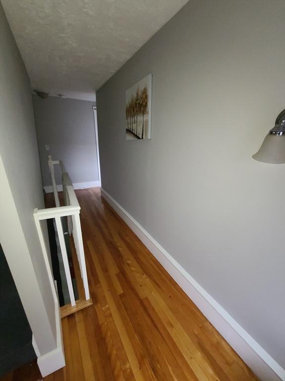 hall with a textured ceiling and hardwood / wood-style flooring