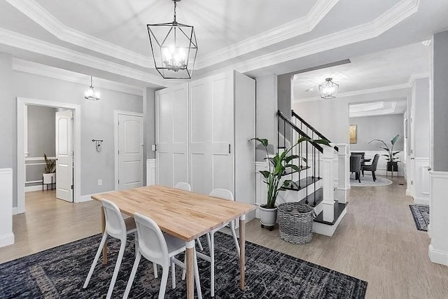 dining area with an inviting chandelier, a decorative wall, wood finished floors, and stairway