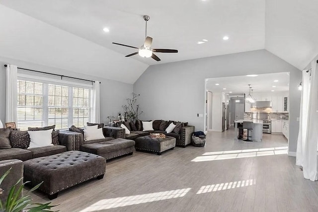 living room with ceiling fan, recessed lighting, light wood-style flooring, and lofted ceiling