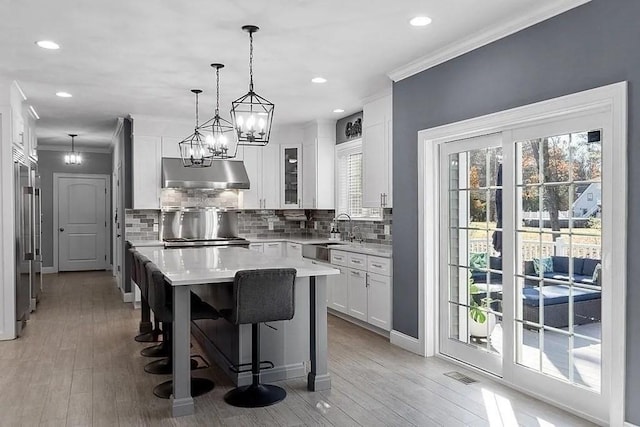 kitchen featuring light countertops, white cabinets, under cabinet range hood, and visible vents