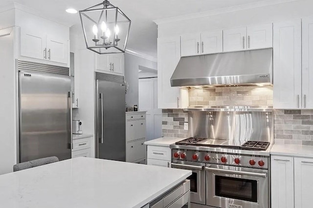 kitchen featuring light countertops, decorative backsplash, under cabinet range hood, and premium appliances