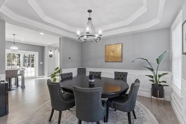 dining room with a tray ceiling, an inviting chandelier, wainscoting, and wood finished floors