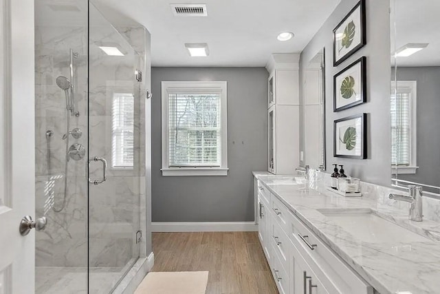 full bathroom featuring a sink, a marble finish shower, baseboards, and visible vents