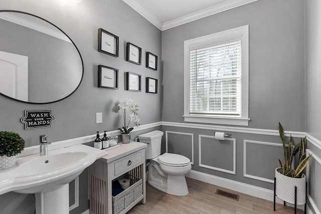 bathroom featuring visible vents, wainscoting, wood finished floors, toilet, and ornamental molding