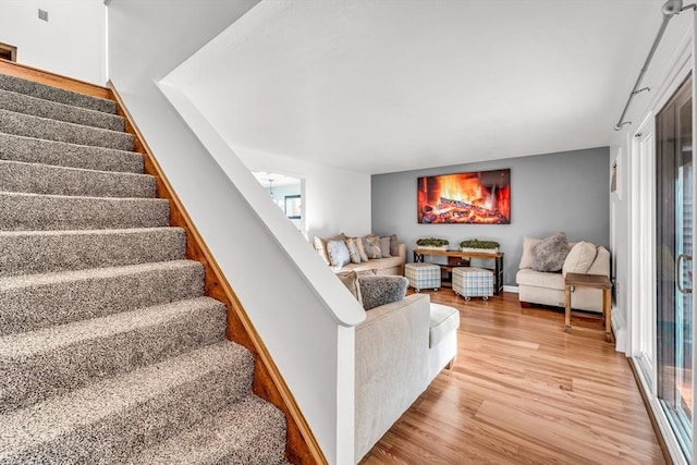 living area featuring stairs, light wood-type flooring, and baseboards