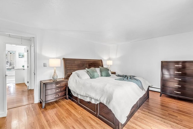 bedroom with light wood finished floors, baseboard heating, and attic access