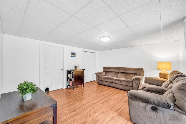 living room with light wood-style floors and a drop ceiling