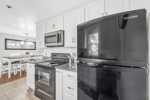 kitchen with black appliances, light tile patterned floors, dark stone countertops, a textured ceiling, and white cabinetry