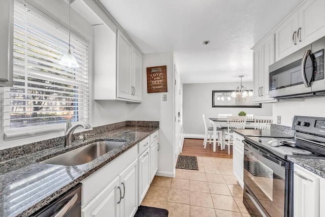 kitchen with pendant lighting, a sink, white cabinetry, appliances with stainless steel finishes, and light tile patterned flooring