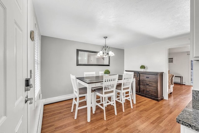 dining room with a textured ceiling, baseboard heating, a chandelier, and light wood finished floors