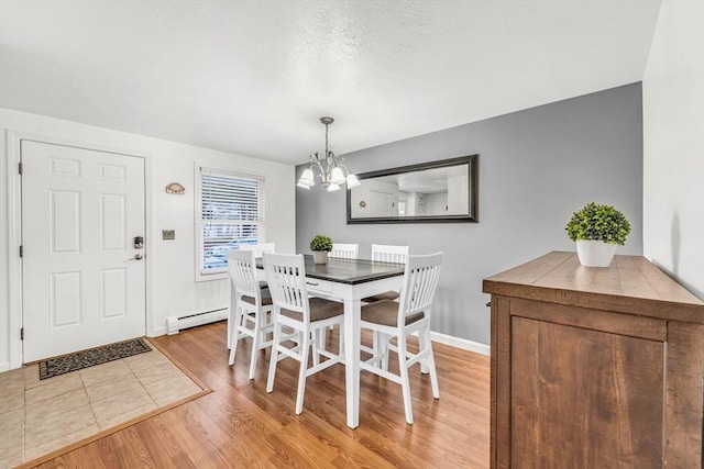 dining room featuring a chandelier, light wood-type flooring, baseboards, and a baseboard radiator