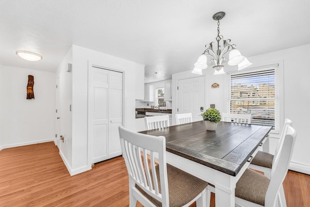 dining room with light wood finished floors, baseboards, and an inviting chandelier