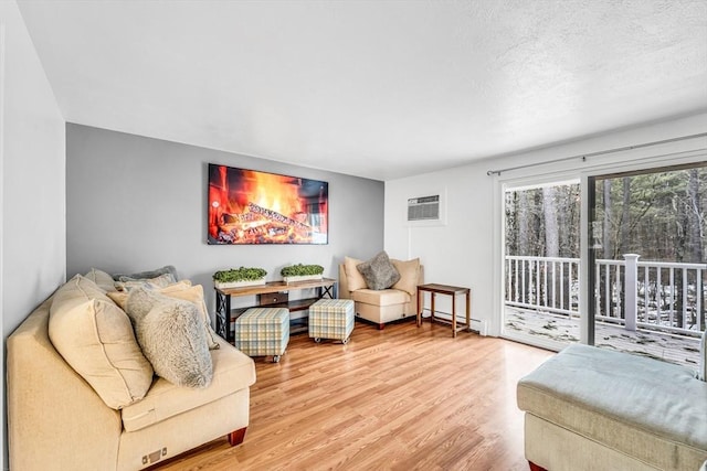 living room featuring a textured ceiling, an AC wall unit, a baseboard heating unit, and wood finished floors