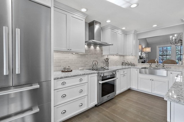 kitchen with a sink, white cabinetry, stainless steel range with electric cooktop, wall chimney range hood, and fridge