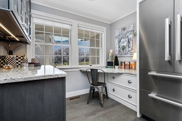 interior space with visible vents, high end fridge, ornamental molding, built in study area, and light stone countertops