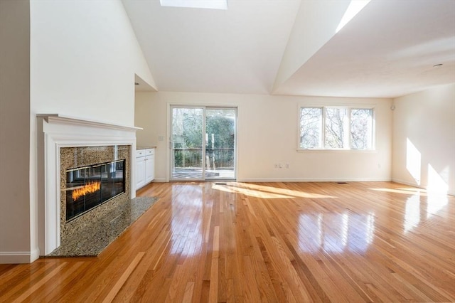 unfurnished living room featuring a healthy amount of sunlight, light wood finished floors, a fireplace, and baseboards