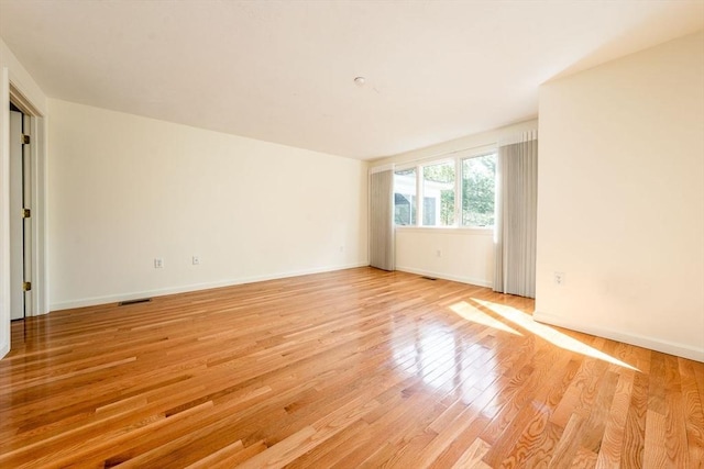 spare room with light wood finished floors, baseboards, and visible vents