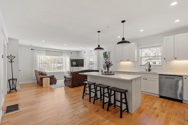 kitchen with sink, stainless steel dishwasher, a center island, and white cabinets