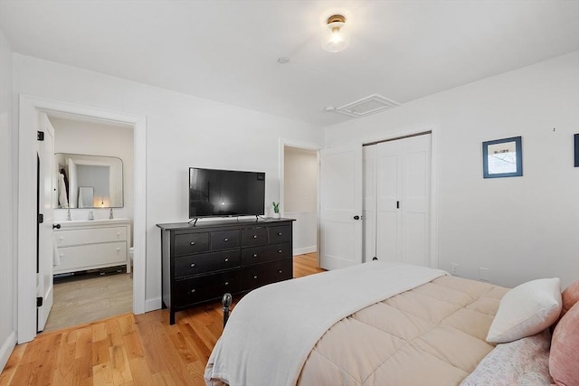 bedroom with ensuite bath, light hardwood / wood-style flooring, and a closet