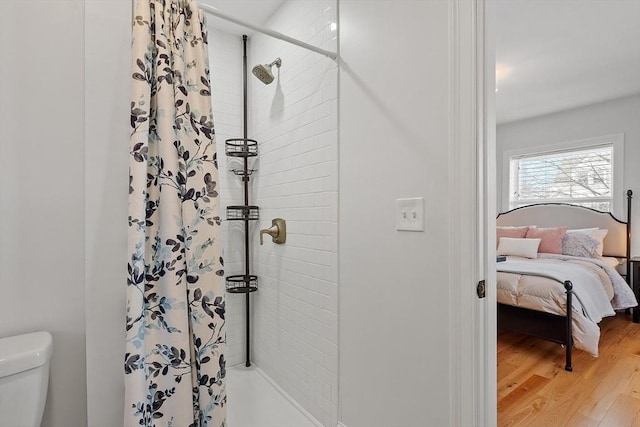 bathroom with wood-type flooring, toilet, and walk in shower