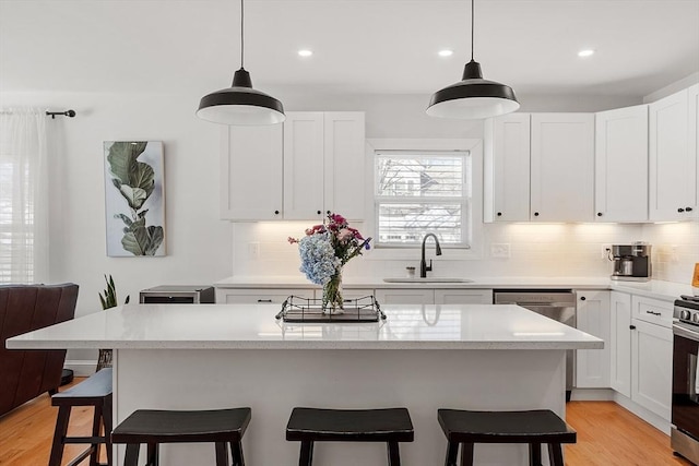 kitchen with sink, dishwasher, white cabinets, and a kitchen island