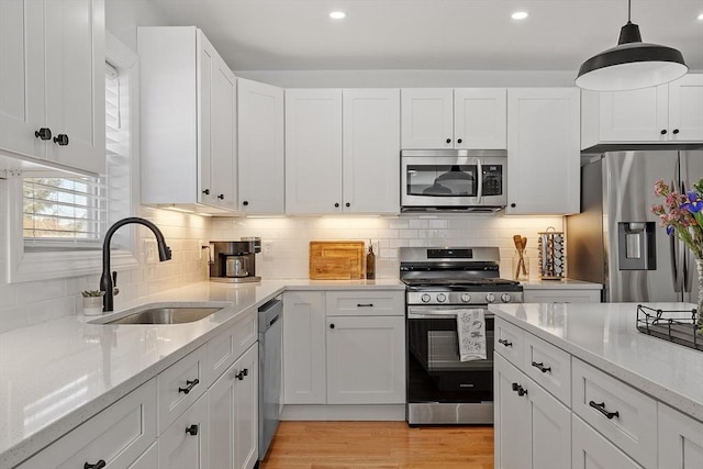 kitchen featuring stainless steel appliances, white cabinetry, sink, and light stone counters