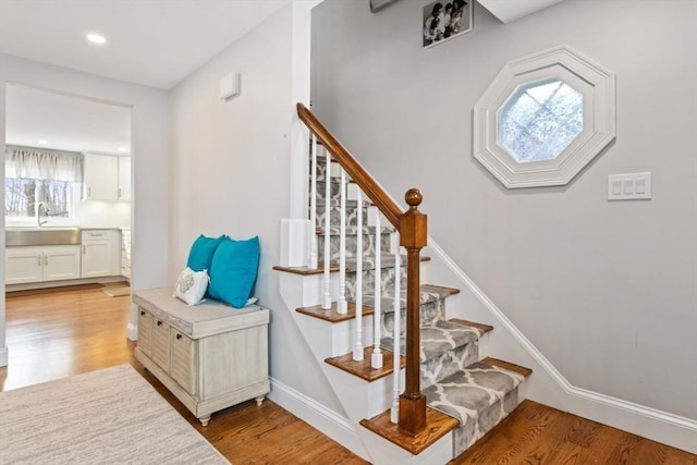 stairs featuring wood-type flooring and sink